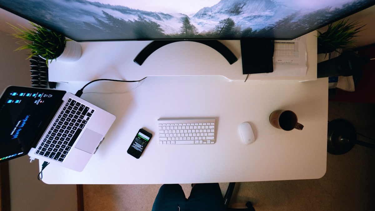 Laptop and smartphone side by side — the operator moving between devices
