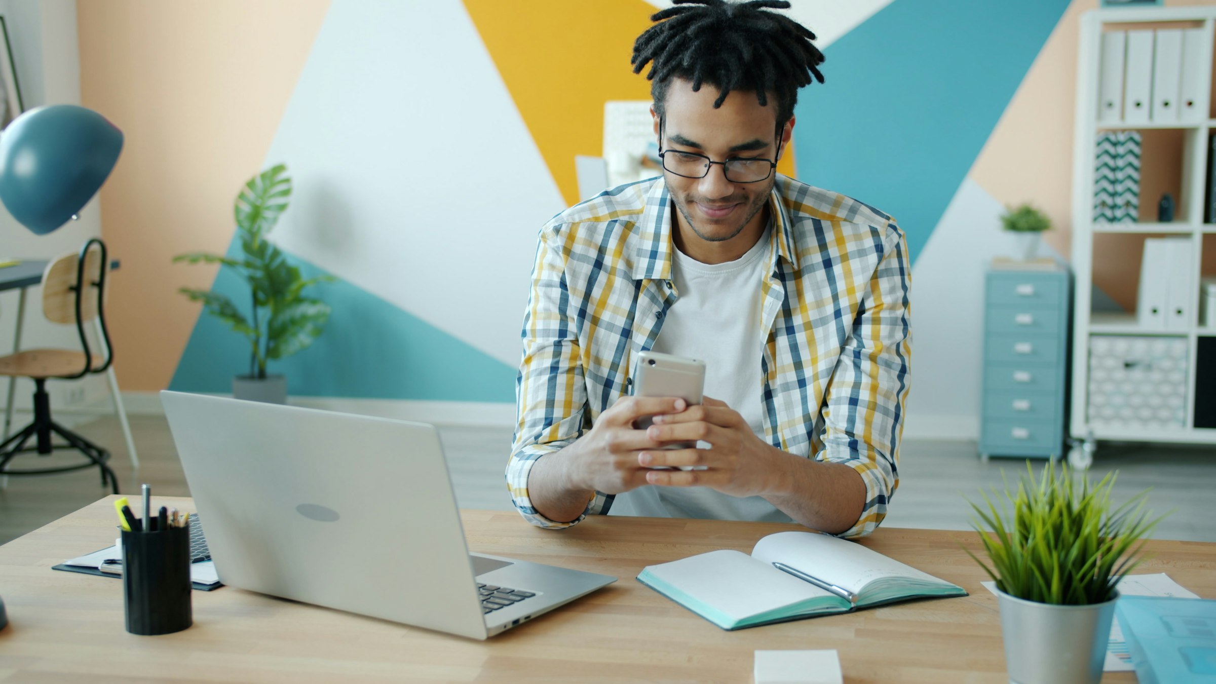 Operator working at a quiet desk with a phone in hand and a laptop nearby